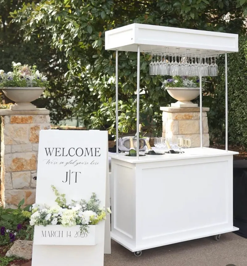 White champagne cart with glasses and welcome sign